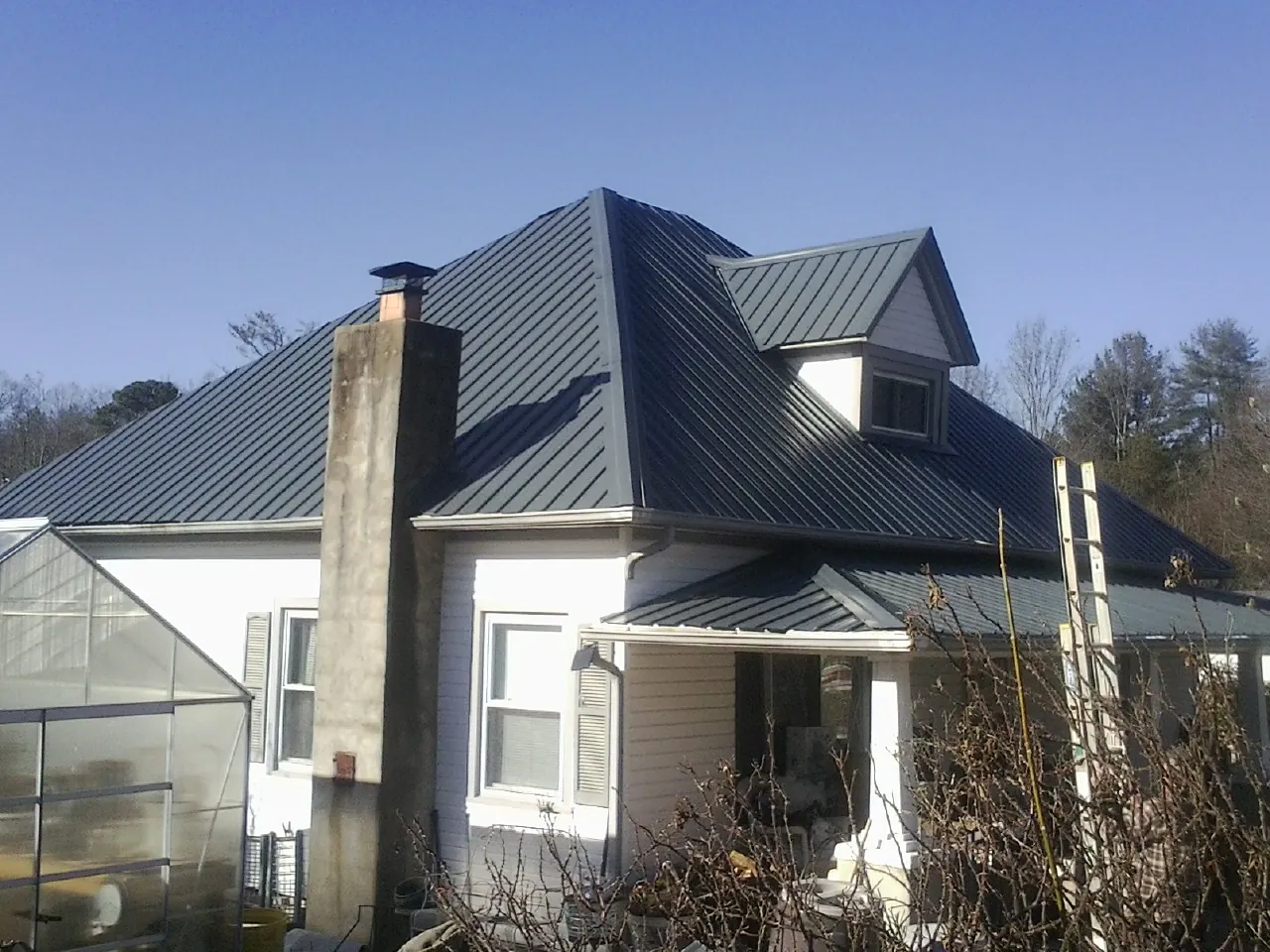 Dark blue standing seam metal roof on a white farmhouse with dormer — Slate & Tile Roof Repair by Roofing Brothers in Pomeroy