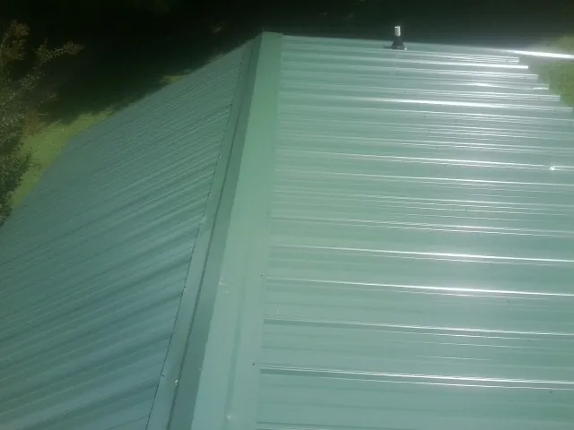 New green metal panels meeting at the ridge of a roof — Flat Roof Repair work by our crew in Pomeroy