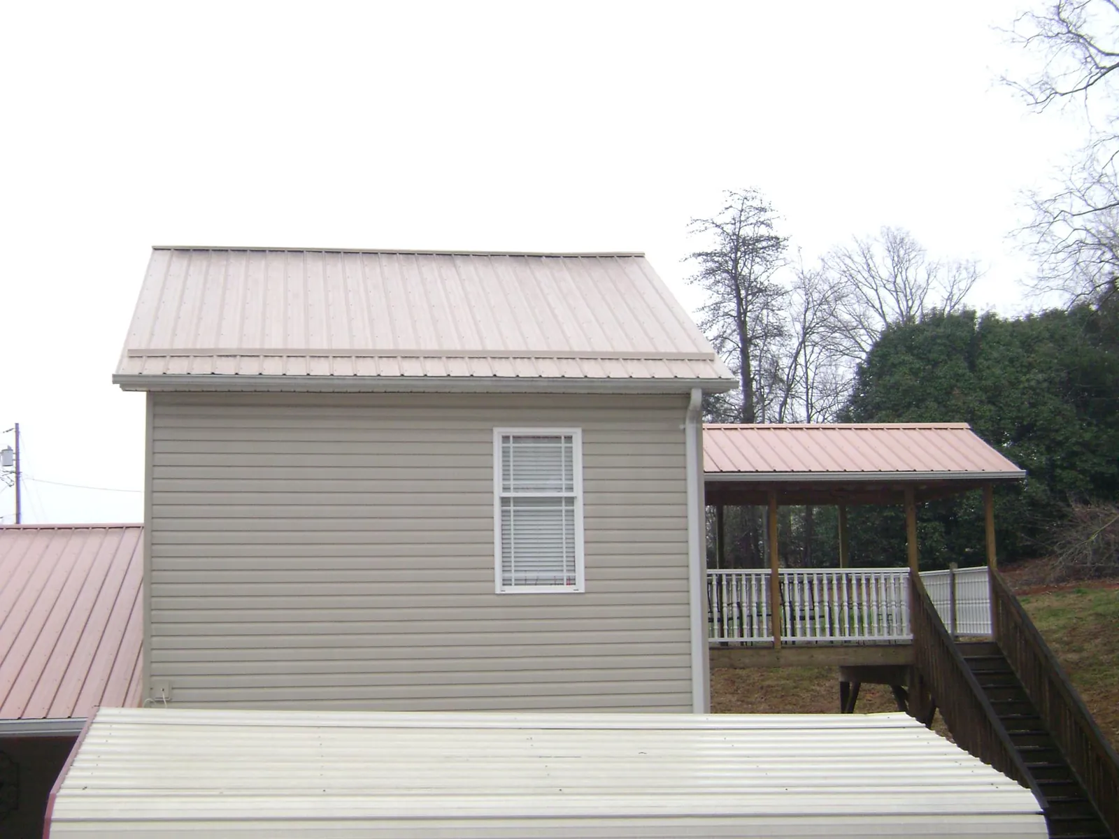 Tan metal roofs on a two story addition and attached porch, from a Roof Replacement job in Pomeroy